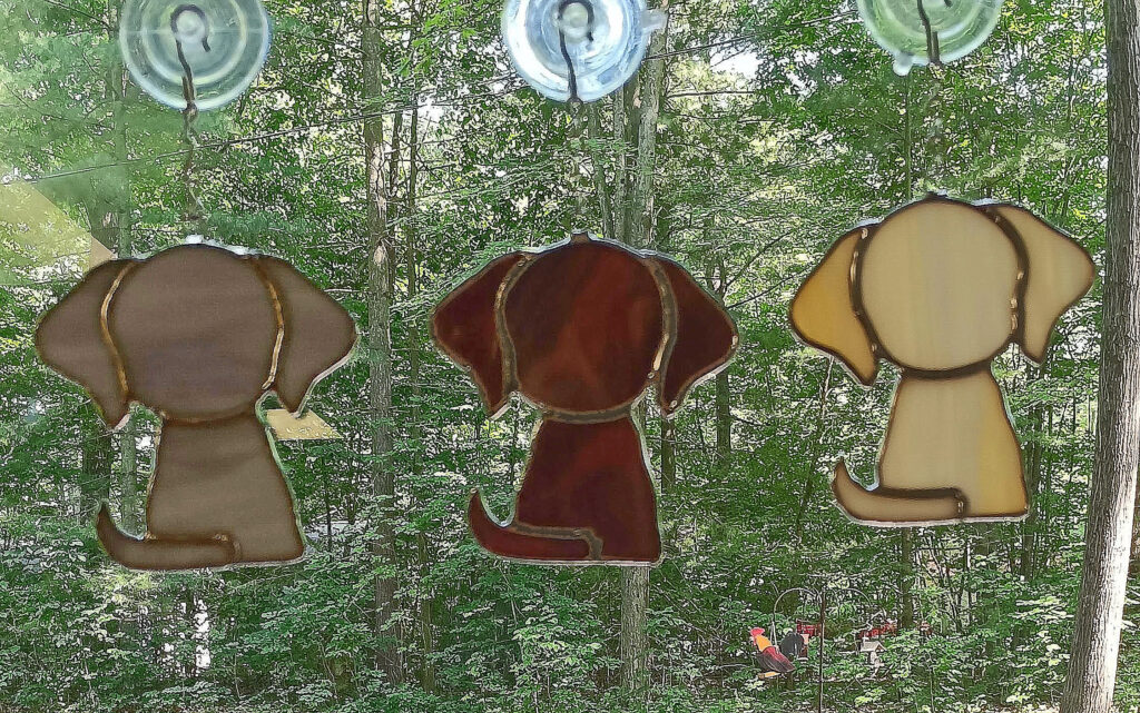 Stained glass Puppies hanging in a window.